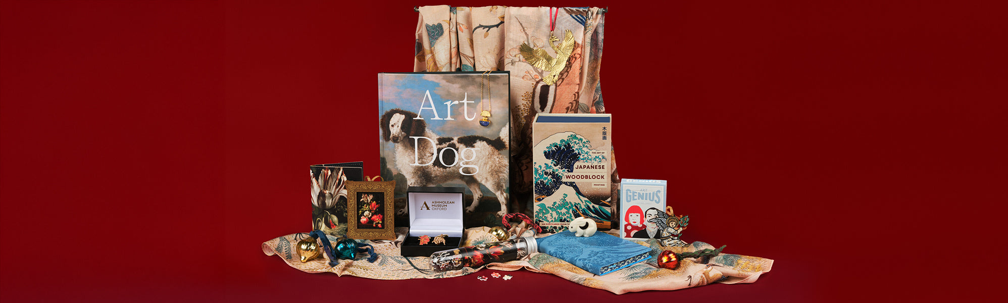 A selection of Art themed gifts, including books, decorations, a scarf, puzzles, and jewellery against a red background.