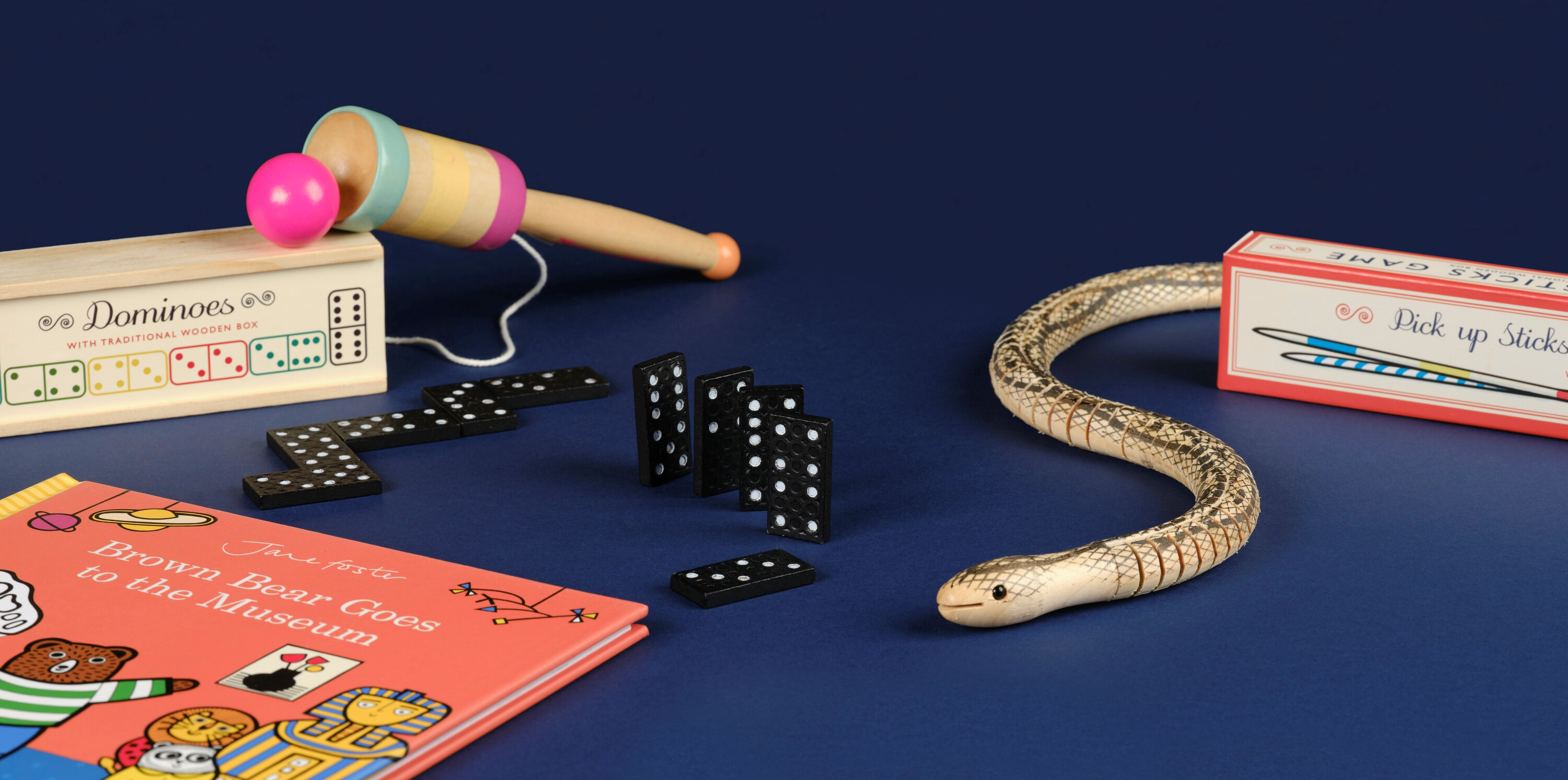 Selection of games including dominos, wooden cup and ball, a wooden articulated snake, pick up sticks and a children's book
