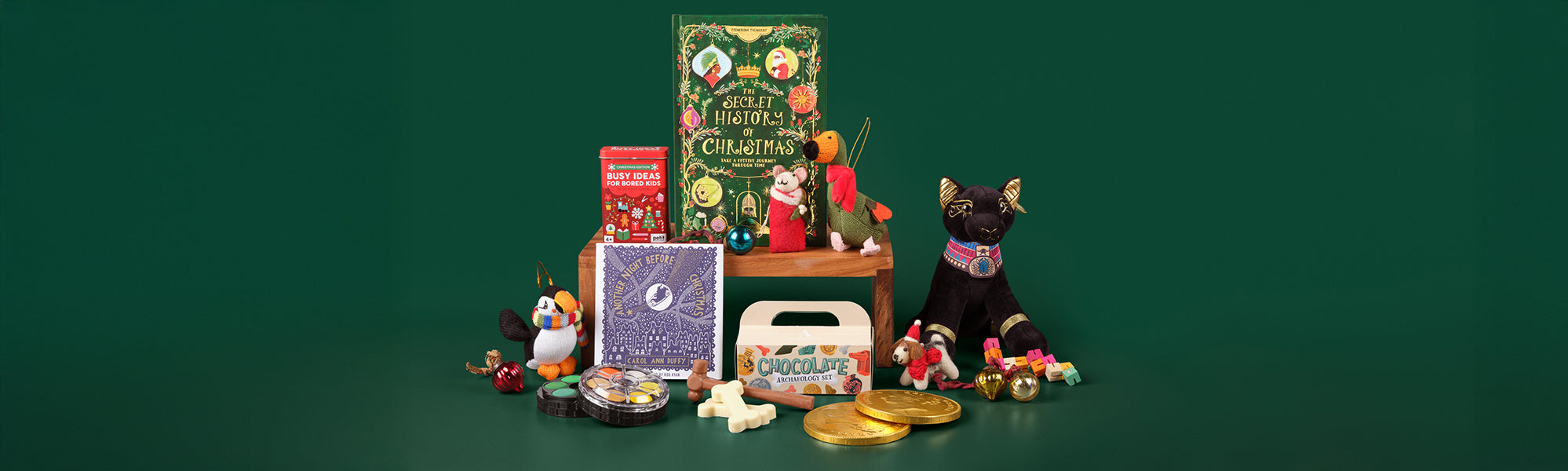 Selection of Children's books, chocolates, decorations, cuddly toys and games against a green background