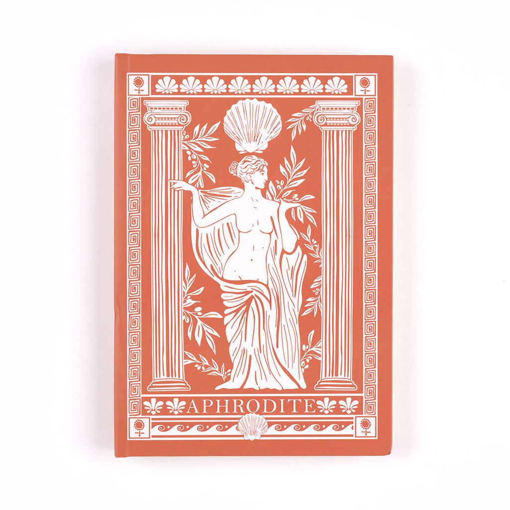 Terracotta A5 sized notebook with white custom Aphrodite pattern of goddess female sculpture surrounded by shells, olive branches, classical columns and Greek pot patterns with the text 'APHRODITE' on a white background.