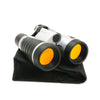 Pair of silver and black binoculars with orange tinted lenses and rubber grips resting on op of black carrying case against a white background.