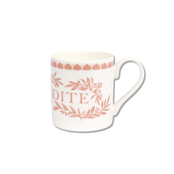 A white ceramic mug featuring a terracotta pink printed design with the word 'DITE' and floral/leaf motifs, set against a plain white background.