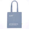 A slate blue canvas tote bag with white printed text reading 'ASHMOLEAN MUSEUM OXFORD' and 'APHRODITE THE MAKING OF A GODDESS'.