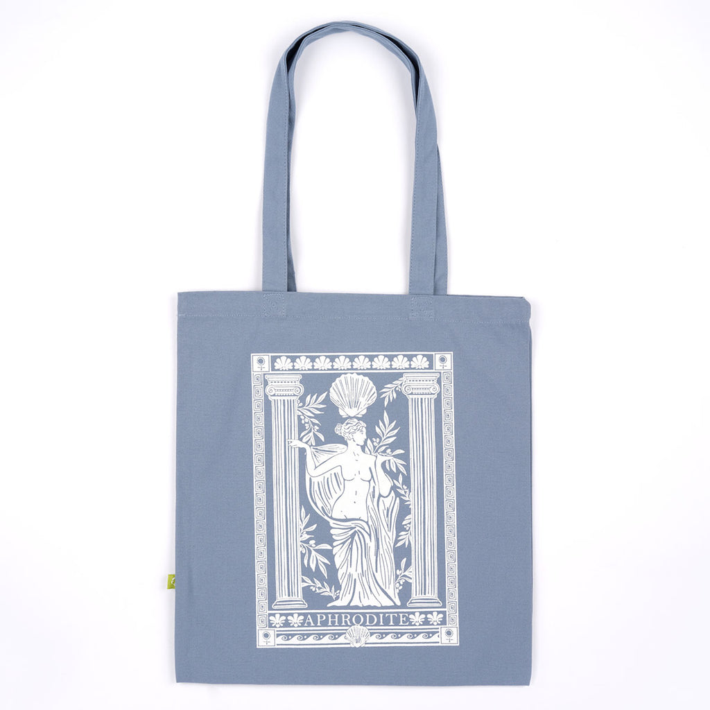 A slate blue canvas tote bag with long handles, featuring a large white graphic print of the Aphrodite statue on the front, set against a plain white background.