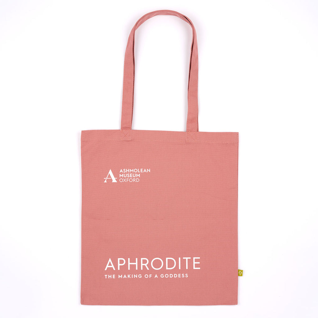 A dusty pink canvas tote bag with white printed text reading 'ASHMOLEAN MUSEUM OXFORD' and 'APHRODITE THE MAKING OF A GODDESS'.