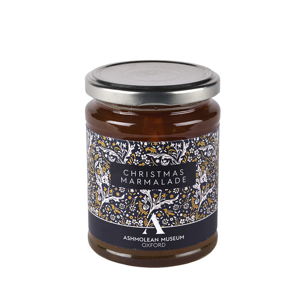 A glass jar of Christmas Marmalade with a silver metal lid and a decorative label featuring a tree pattern in navy, gold, and white. The label reads 'CHRISTMAS MARMALADE' and 'ASHMOLEAN MUSEUM OXFORD'.