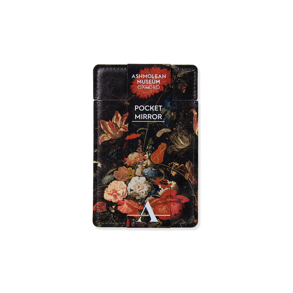 Oblong shaped pocket mirror with Dutch still life flowers artwork with bold reds oranges and pink colours with contrasting dark black backdrop against a white background.