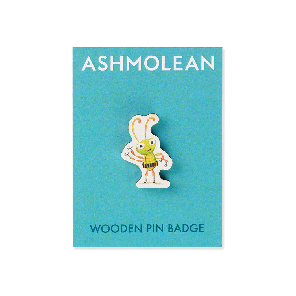 A wooden pin badge featuring a cartoon Beetle character wearing a green shirt and yellow-and-black striped tool belt, displayed on a turquoise Ashmolean branded backing card.