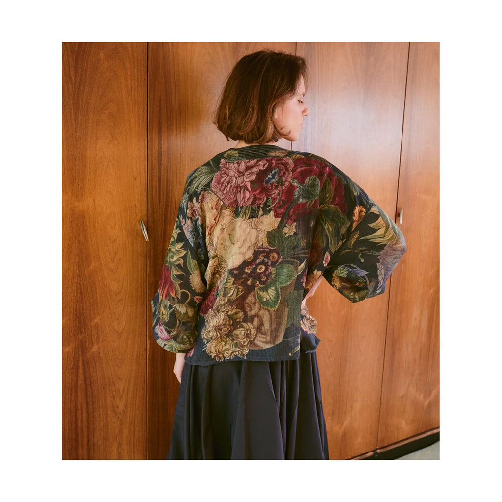 Person wearing a floral patterned wool kimono in front of wooden doors with their back turned away to show the back design
