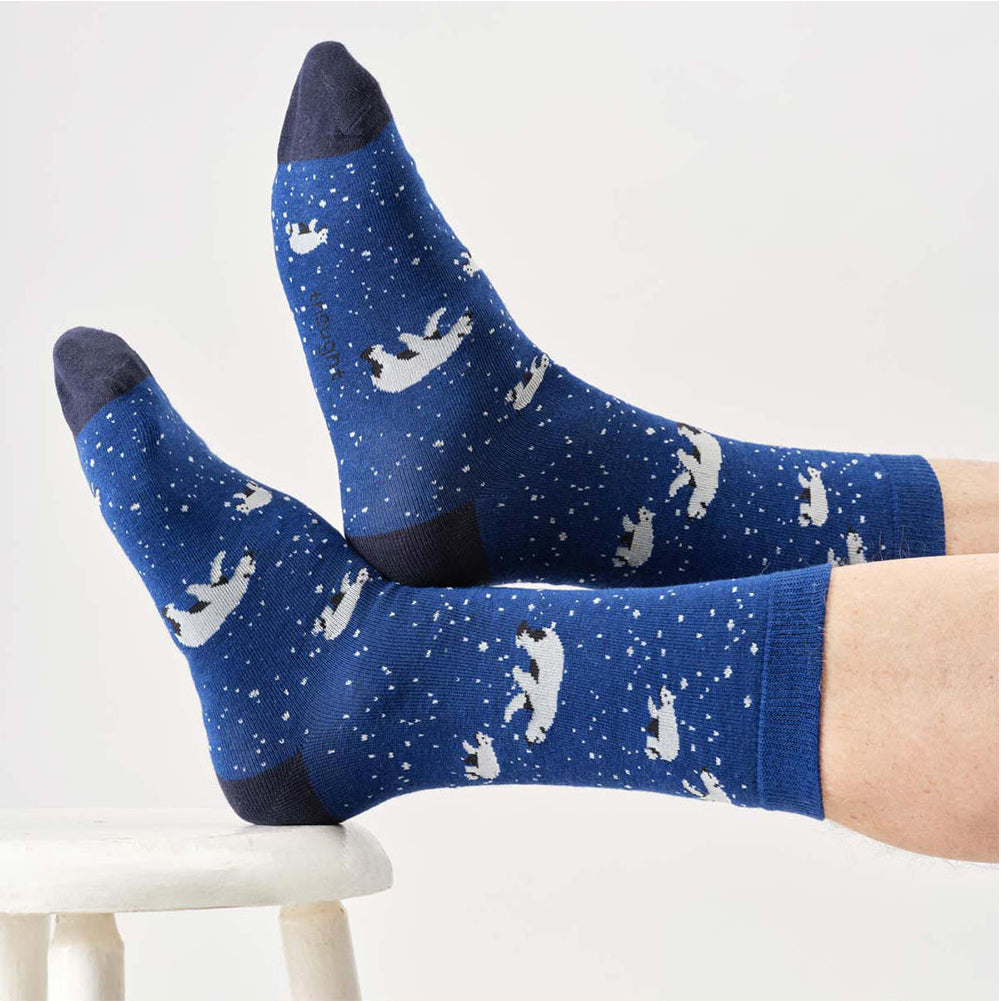 Blue socks with white polar bear patterns worn by a person on a white background
