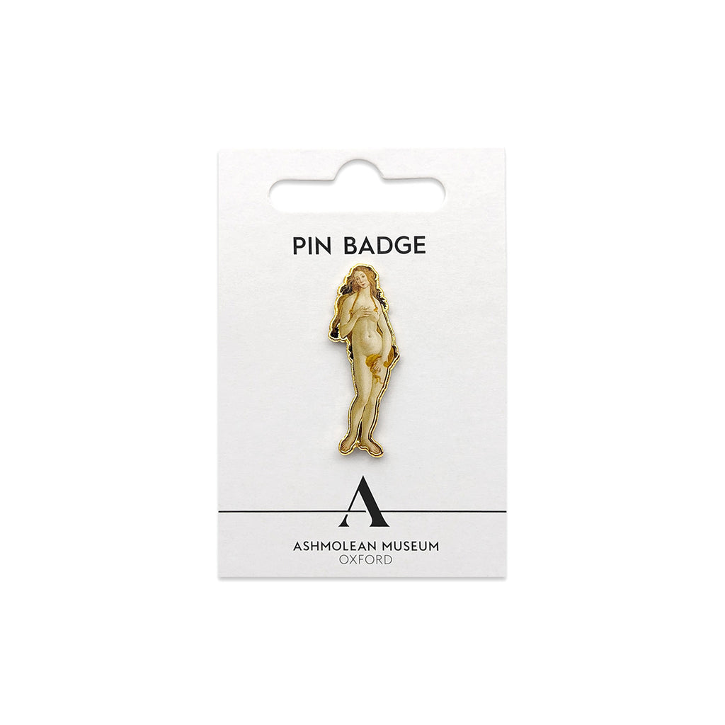 A gold-toned pin badge depicting a classical nude female figure, mounted on a white Ashmolean Museum Oxford display card.