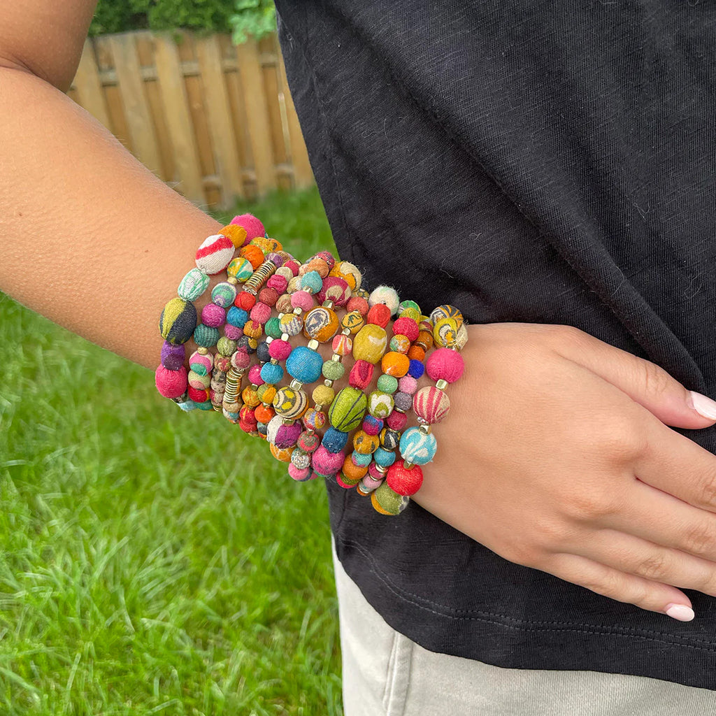 Colorful beaded bracelets on a person's wrist with a grassy background
