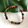 Colorful beaded bracelet with gold accents on a leafy background