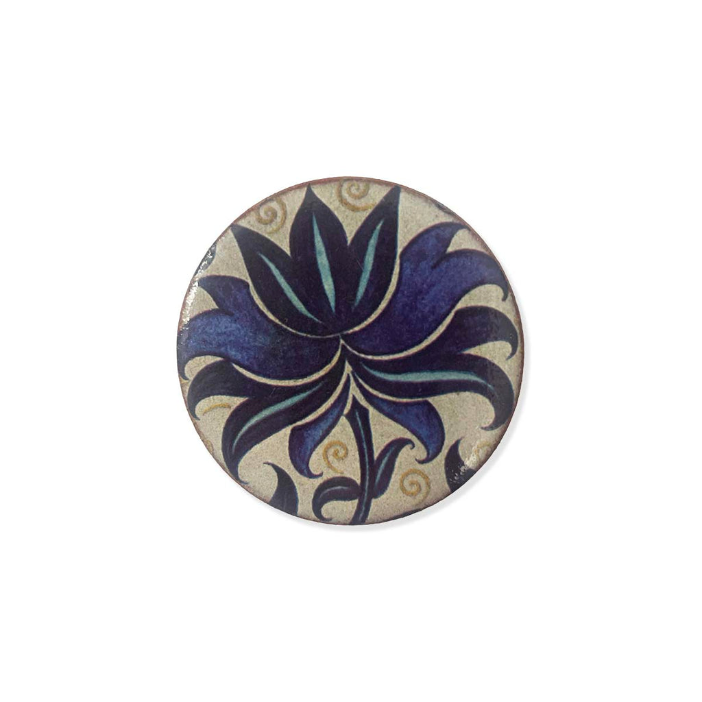 Round ceramic brooch with floral design on a white background