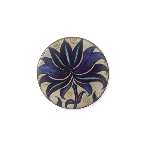 Round ceramic brooch with floral design on a white background