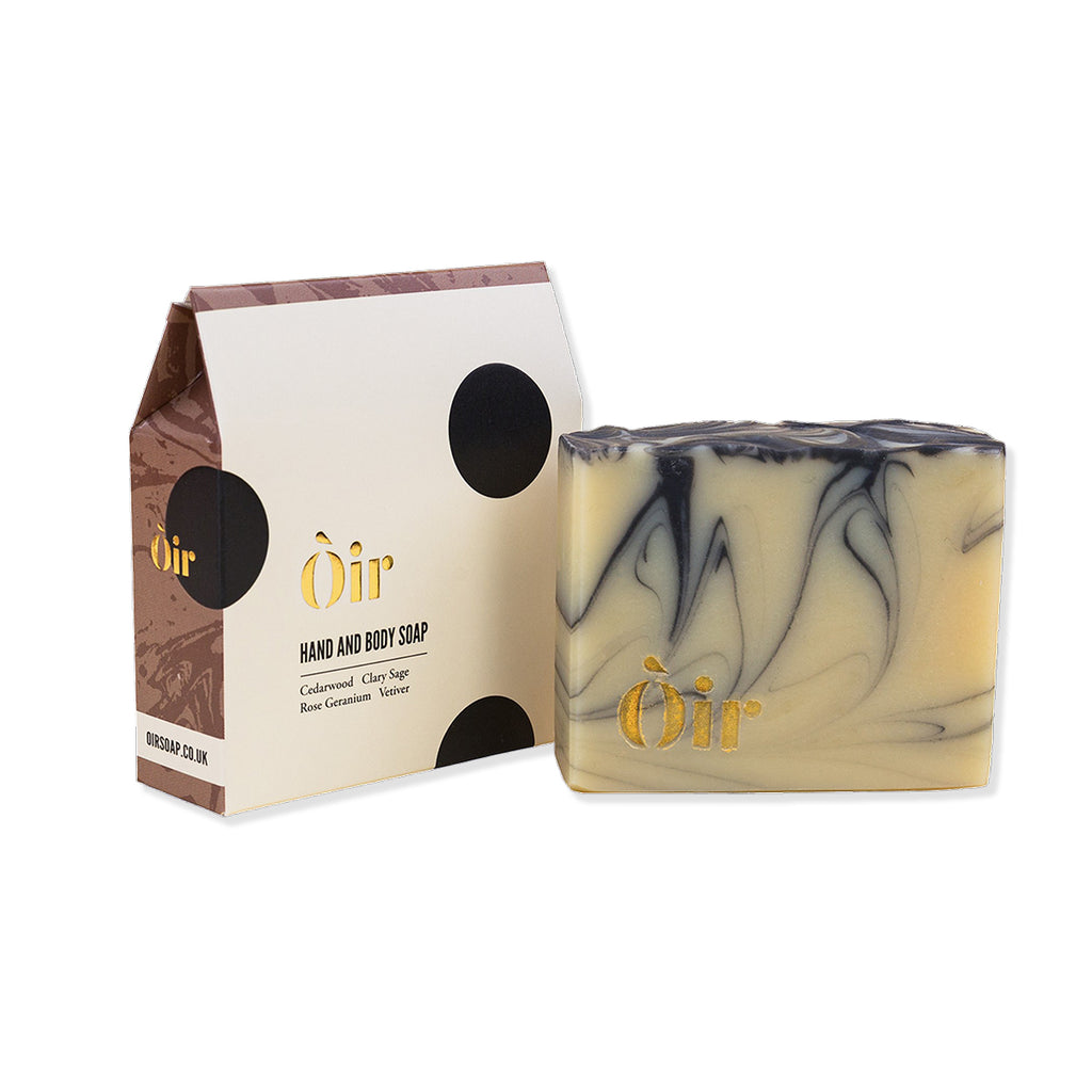 Marbled hand and body soap with 'Oir' branding next to its packaging on a white background