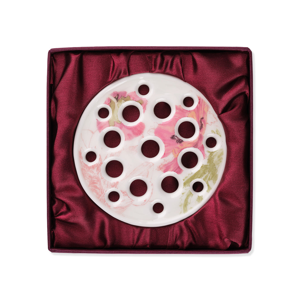 White ceramic halliesphere flower arranger with colourful may Morris poppy design inside of a red velvet gift box against a white background.