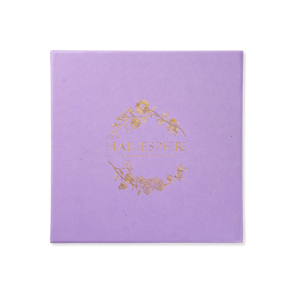 Purple square gift box with inlaid gold text 'HALLIESPHERE' and golden flowers on a white background.