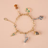 Gold bracelet with various charms on a beige background