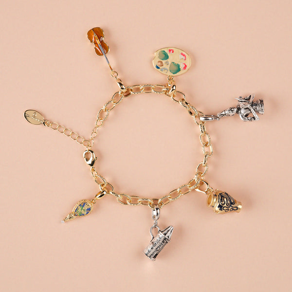 Gold bracelet with various charms on a beige background