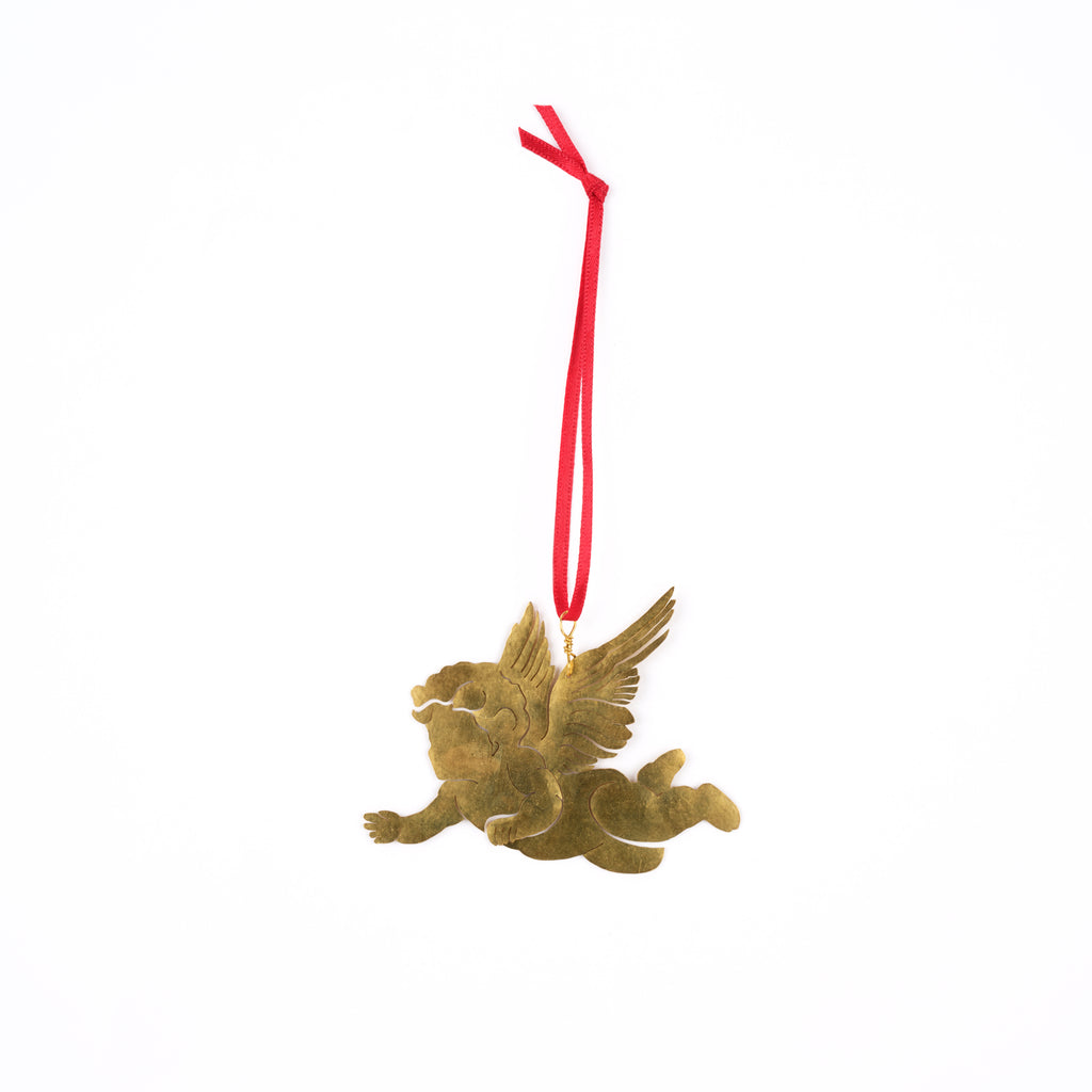 A small winged cherub ornament in a metallic gold finish, suspended by a red hanging ribbon against a plain white background.