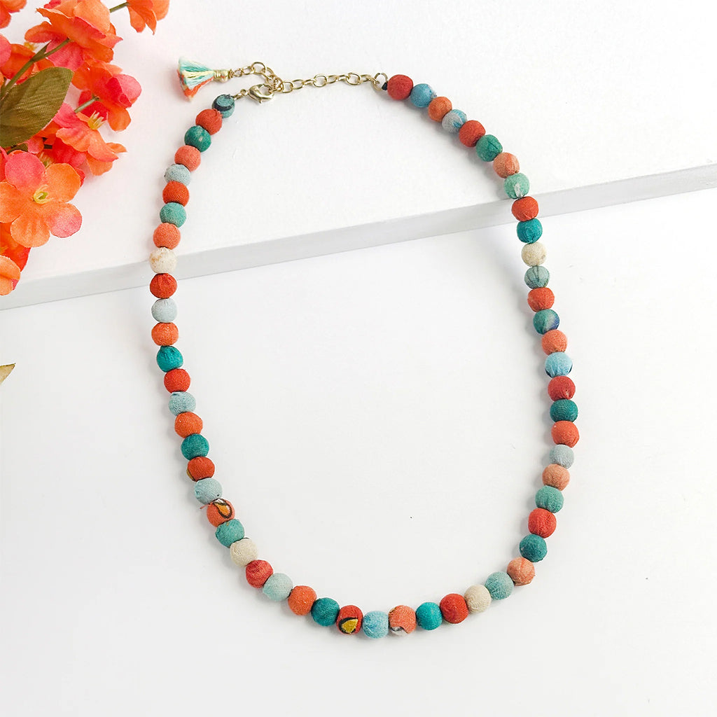Colorful beaded necklace on a white background with flowers.