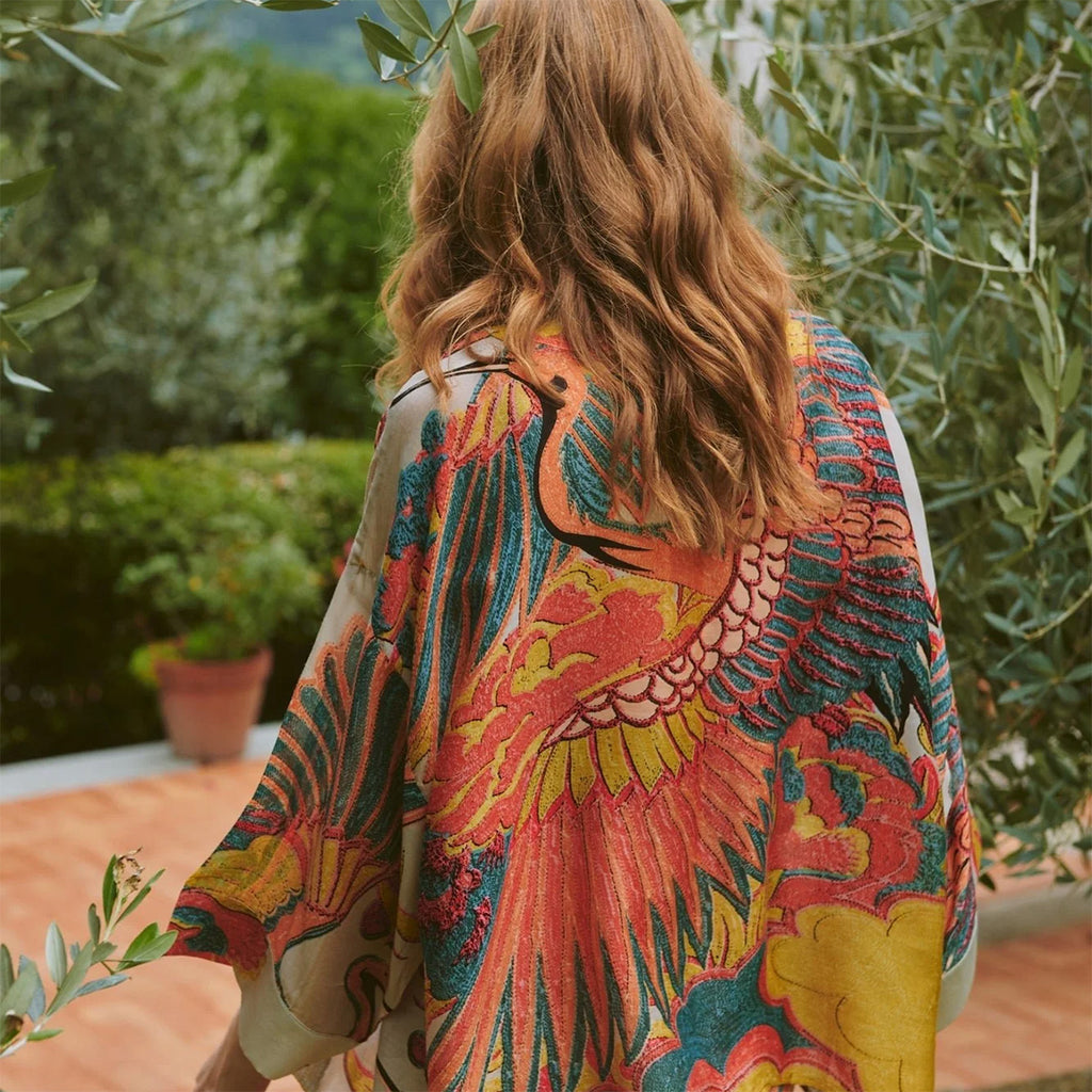 Person wearing a colorful kimono-style garment with a garden background