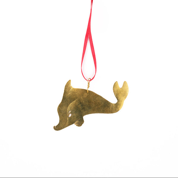 Hammered brass decoration with a dolphin design and red ribbon on a white background.