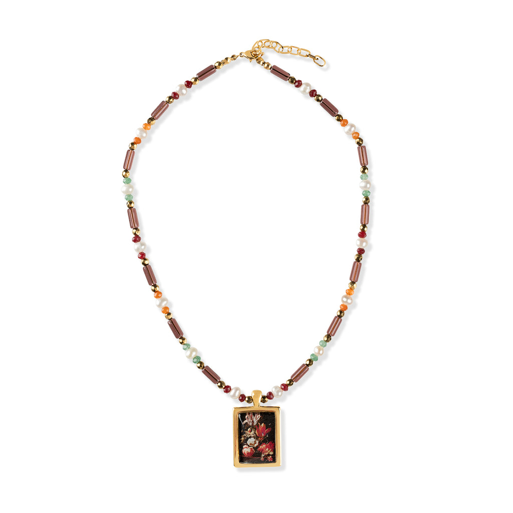 Gold metal and gem stone necklace with multi-coloured gemstones and golden pendant of flower painting on a white background.