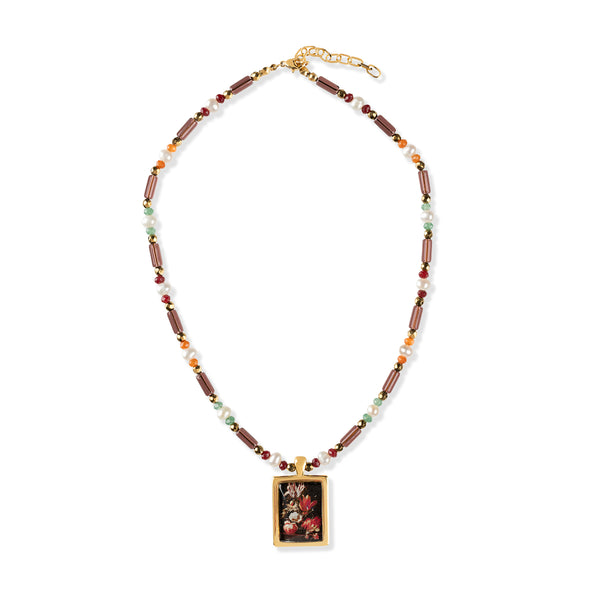 Gold metal and gem stone necklace with multi-coloured gemstones and golden pendant of flower painting on a white background.