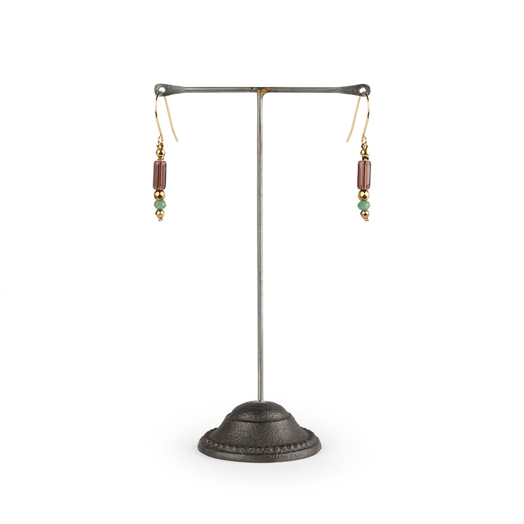 Pair of earrings on a metal stand against a white background