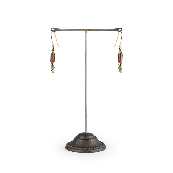 Pair of earrings on a metal stand against a white background