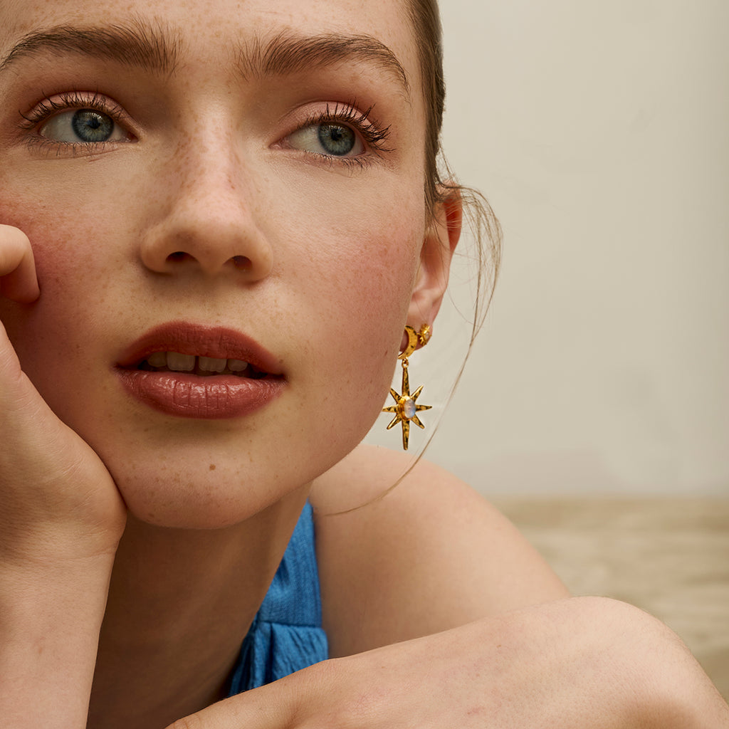 Close-up of a woman wearing gold earrings with a star design.