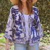 model wearing white and blue kimono jacket over jeans and t shirt in front of olive plants