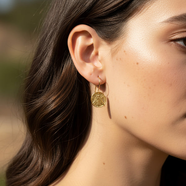 Close-up of a woman wearing gold earrings with a blurred natural background