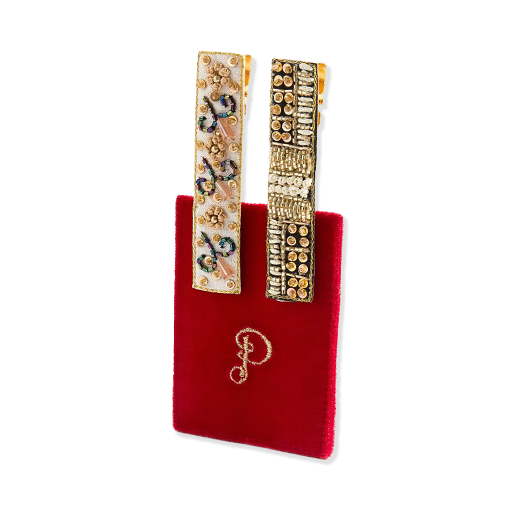Decorative hair clips on a red velvet pouch with a gold logo.