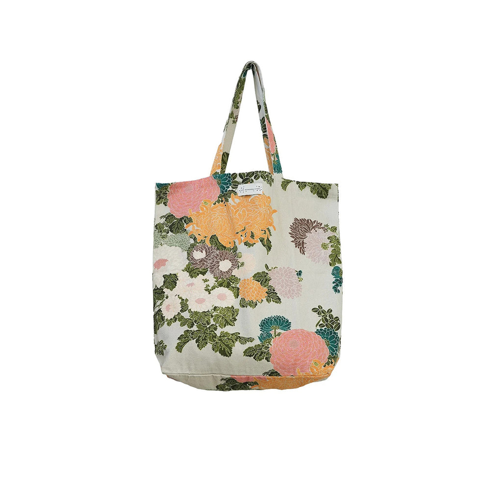 A canvas tote bag with a multicolor floral print featuring pink, orange, and green flowers on a light cream background, shown against a plain white background.