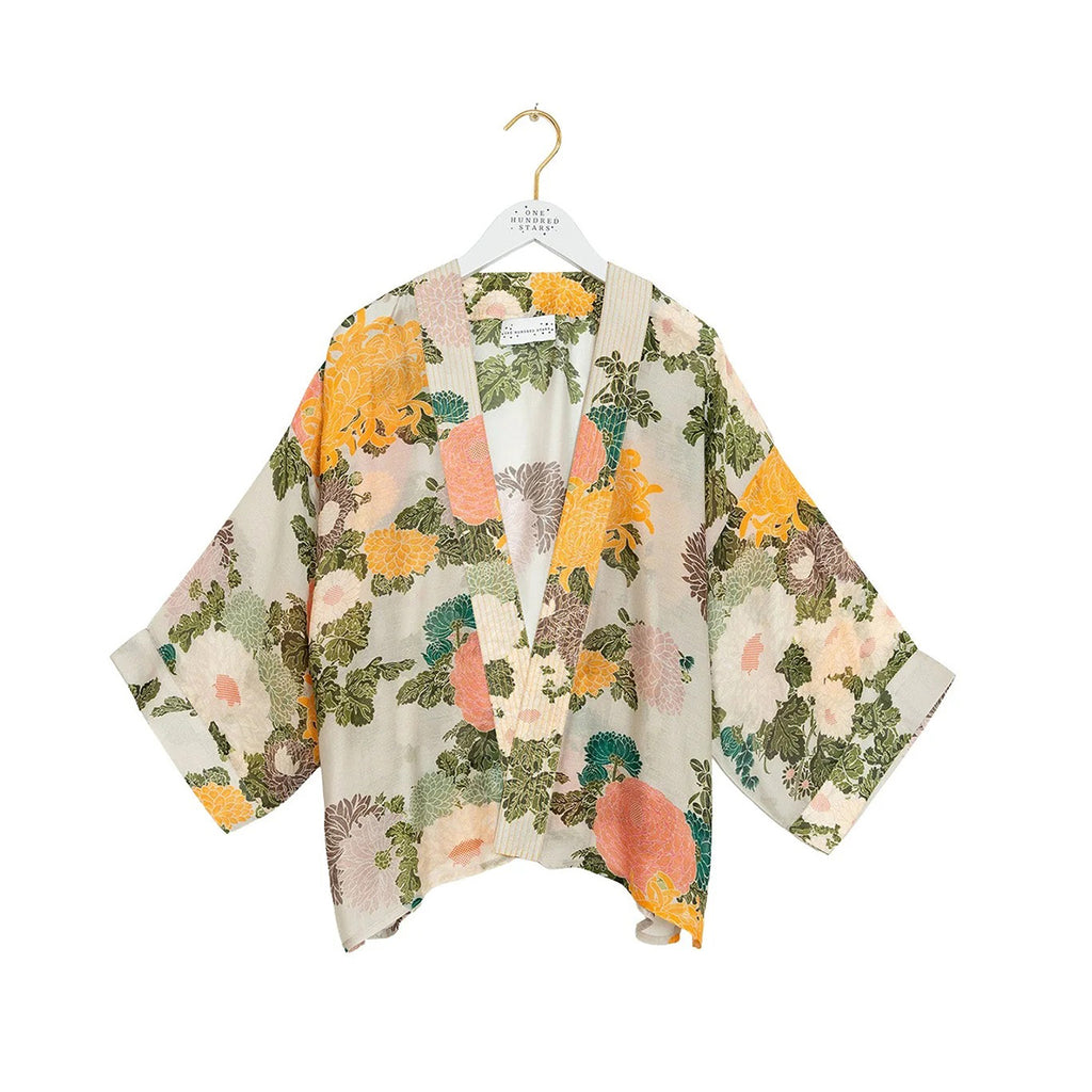 A lightweight open-front kimono-style top with wide sleeves, featuring a multicolor floral and botanical print on a cream base. The print includes orange, pink, green, and brown elements.