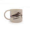 White mug with black brushstroke design against a white background