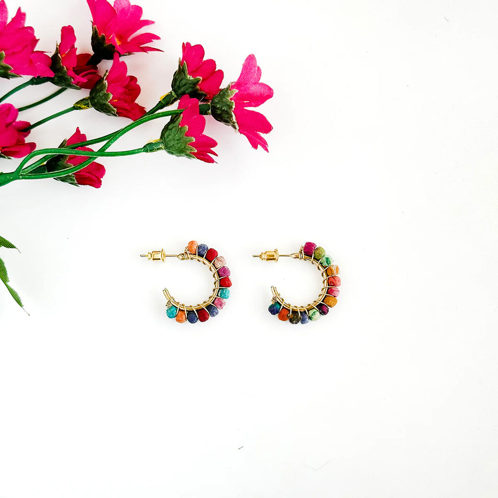 Colorful hoop earrings on a white background with pink flowers.