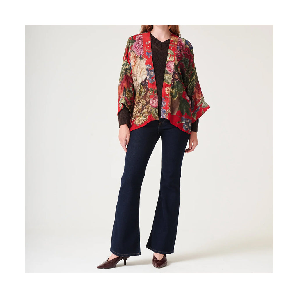 Person wearing a colorful floral jacket and dark pants on a white background