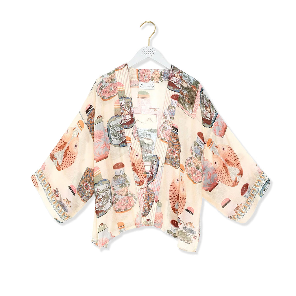 Neutral tone kimono with perfume bottles, fish and flowers art pattern on a white background.