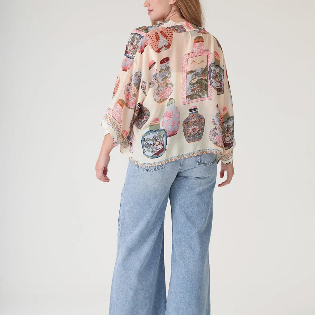 Model turned around to show back of perfume bottle kimono with fish and floral pattern on a white background.