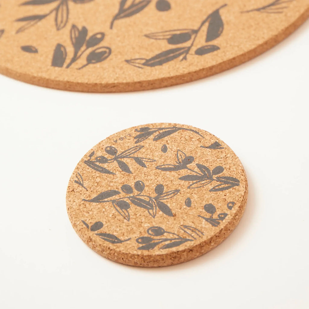 Round cork coaster and placemat with dark grey olive leaf branch pattern on a white background