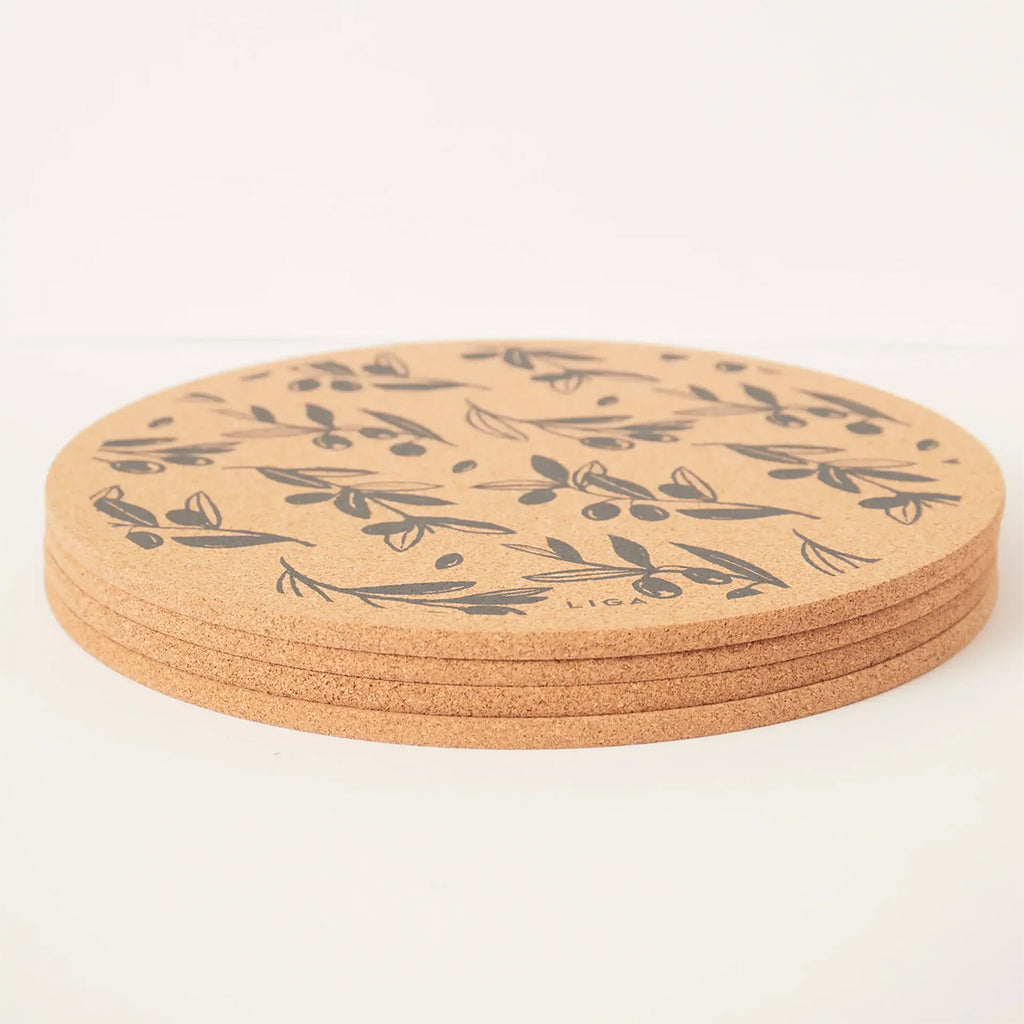 A stack of round cork placemats with a dark grey botanical olive leaf pattern, displayed on a clean white background.