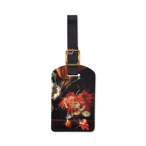 Floral luggage tag with gold Ashmolean Museum Oxford logo embossed and black strap on a white background