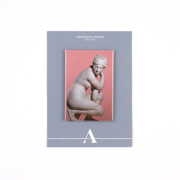 A rectangular Ashmolean Museum decorative fridge magnet with a grey border, featuring a central print of a classical crouching statue against a pink background.