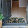 Lifestyle shot of green floor mat with May Morris floral design inside of home doorway. 