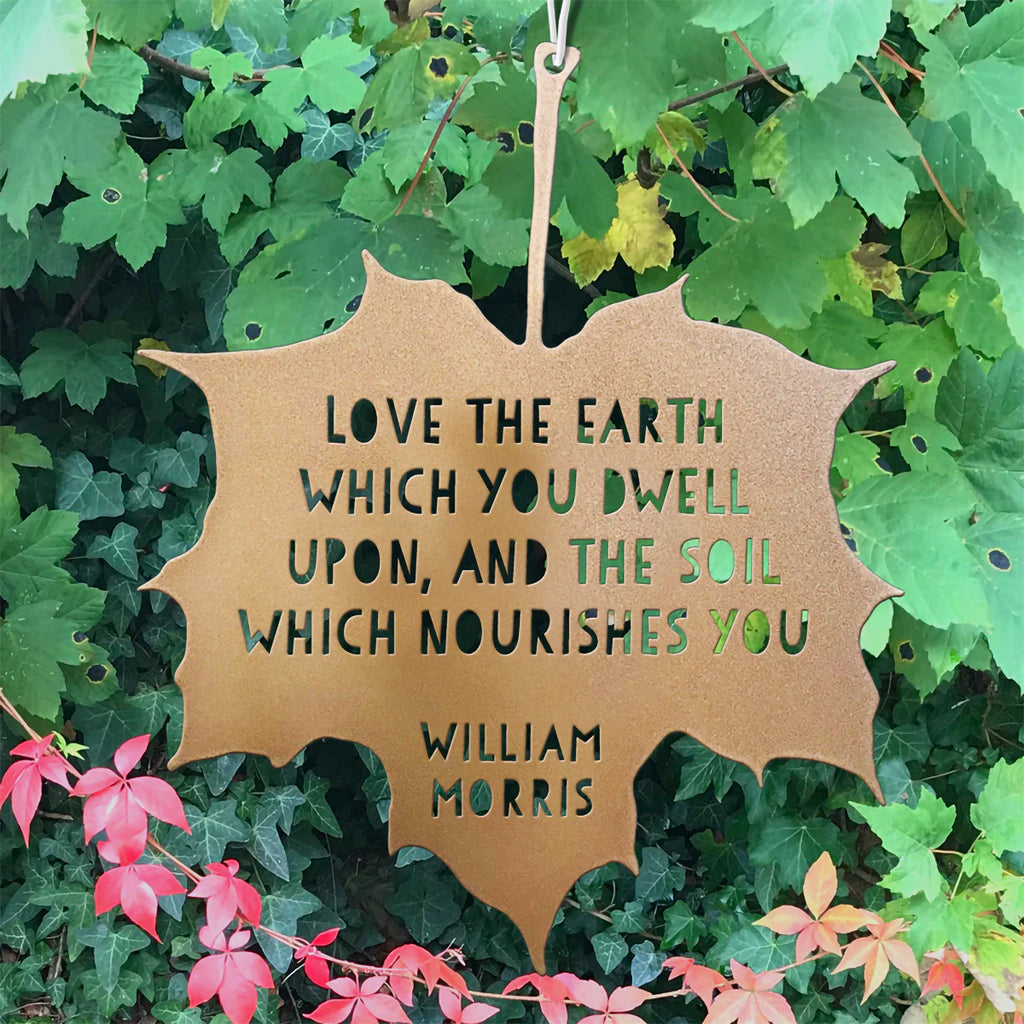 Decorative leaf-shaped sign with a quote by William Morris on a green leafy background