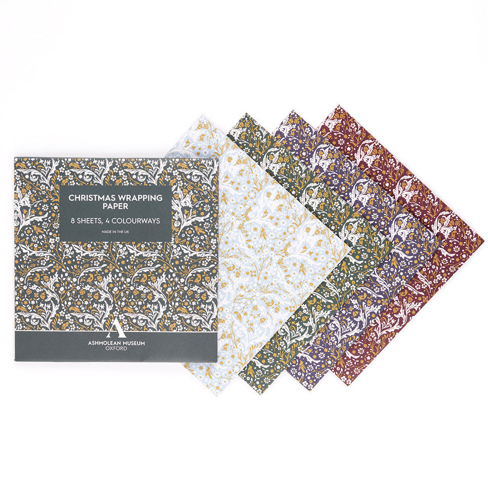 A set of four patterned Christmas wrapping paper sheets with their packaging box, displayed on a clean white background. The papers feature festive patterns in gold, green, blue, and red.